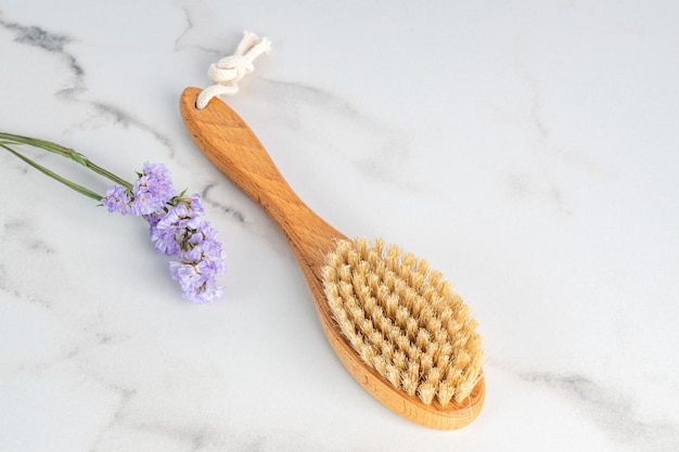 Dry massage brush with natural bristle on marble backgorund ecolodical cosmetics home care spa procedures