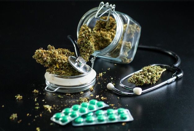 Dry medical cannabis in a jar with a stethoscope on a black background