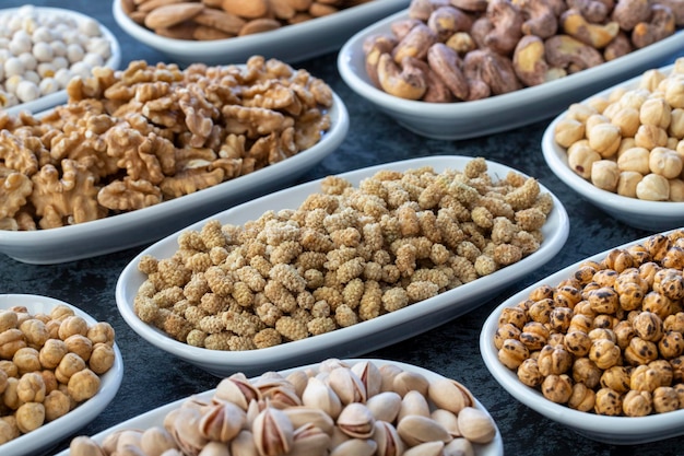 Dry Mulberry in selective focus Nuts on plate on a dark background Walnut Chickpeas White Chickpeas Dry mulberry almond cashew pistachio Types of nuts on the plate