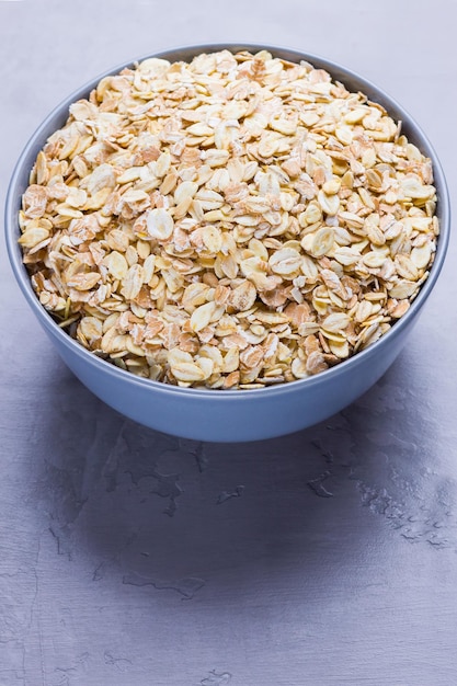 Dry oatmeal in bowl Oat flakes on cement background Cereals for making healthy breakfast Copy space