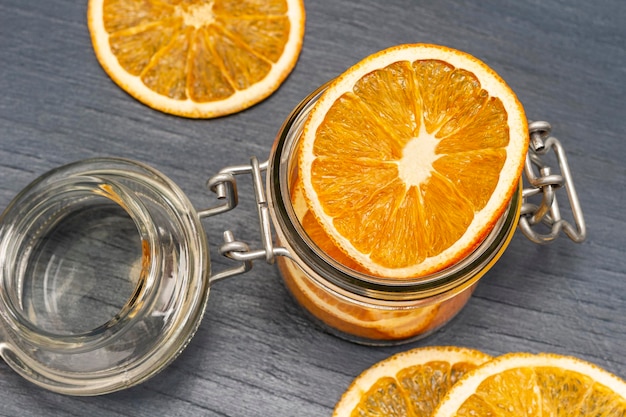 Dry orange slices in glass jar and on table