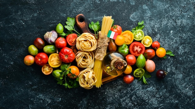 Dry pasta tomatoes greens oil and ingredients Italian traditional cuisine Fresh vegetables Top view Free space for your text