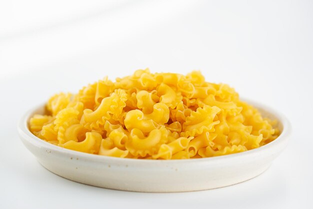 Dry raw pasta Creste Di Gallo in a plate on a light background