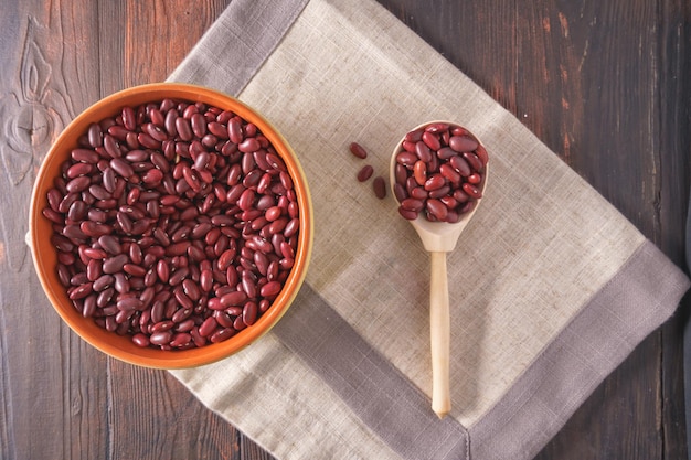 Dry Red beans in a bowl and a spoon on wooden background top view