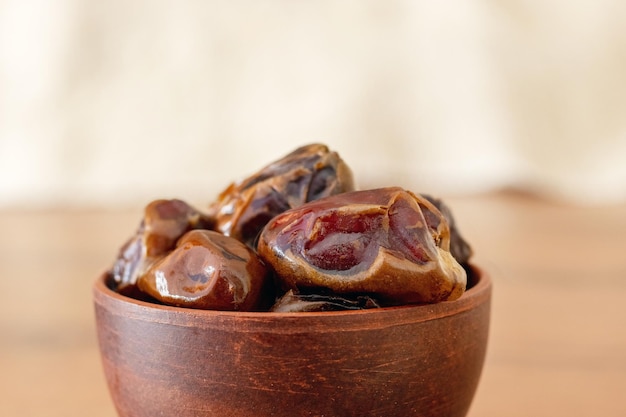 Dry tasty dates in a brown ceramic cup on a blurred background