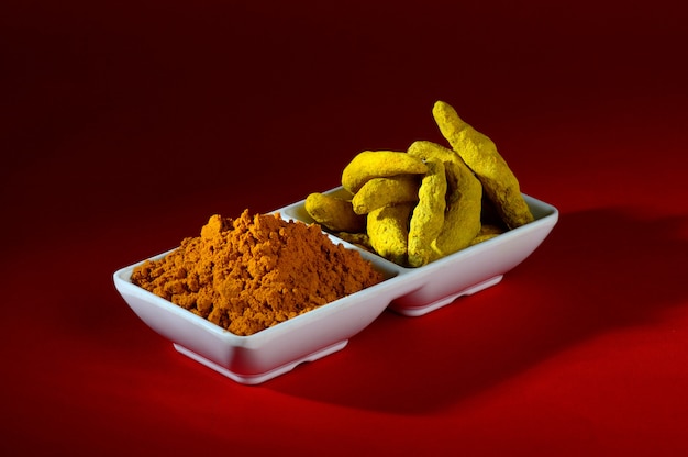 Dry Turmeric powder and roots or barks in white plate