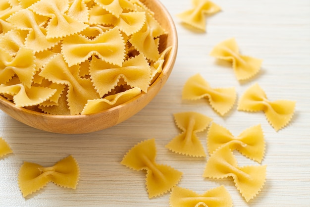 Dry uncooked farfalle pasta in wooden bowl