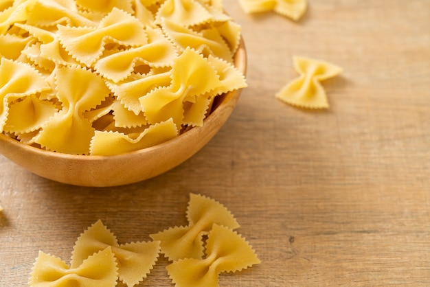 Dry uncooked farfalle pasta in wooden bowl