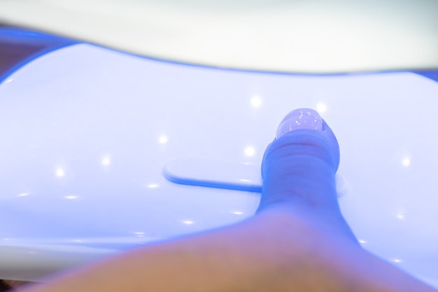 Drying nails after applying varnish in a special ultraviolet dryer