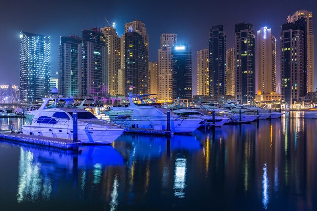 Photo dubai  marina boats moored in canal by illuminated buildings in city at night