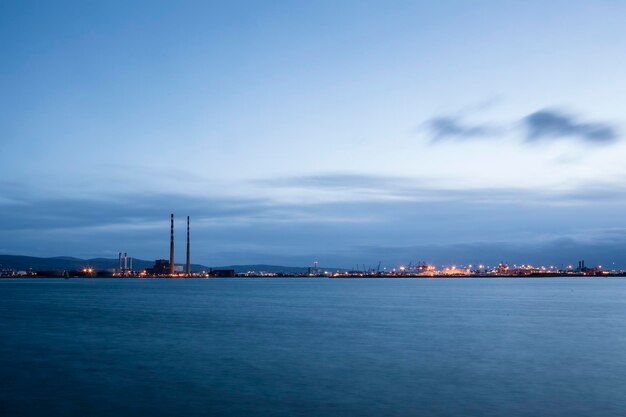 Dublin city at waterfront against cloudy sky