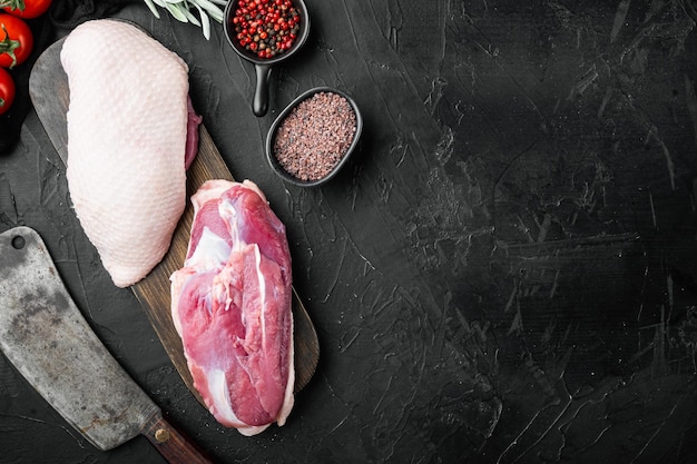 Duck breast raw fillet meat with old butcher cleaver knife on black stone background