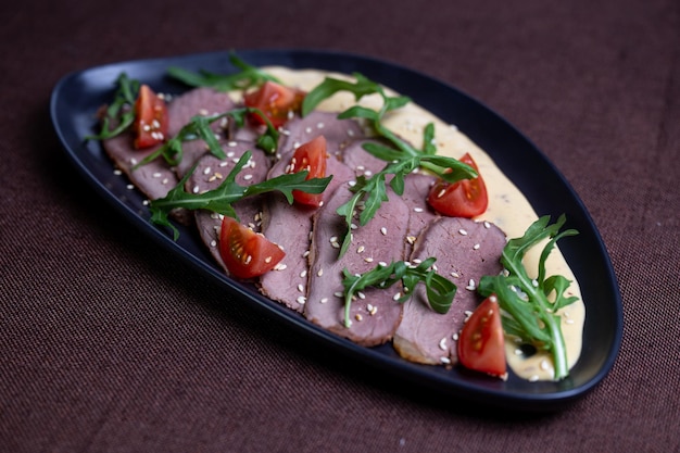 Duck breast with arugula cherry tomatoes and sesame seeds on a creamy sauce