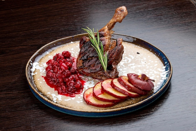 Duck leg with winecherry sauce and baked apple On a wooden background