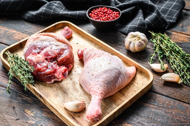 Duck  legs on cutting board, Raw meat. Dark background. Top view.