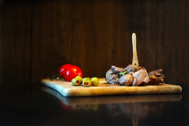 Duck meat with tomatos and olives on a wooden board Gourmet tasty food and cooking concept