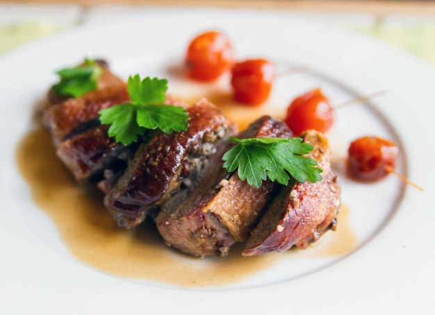 Duck roll in demiglace sauce decorated with parsley leaves on a plate