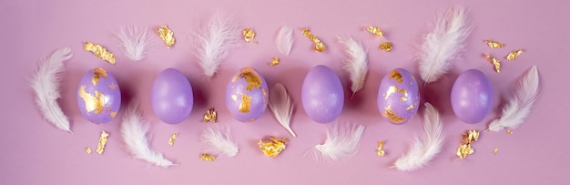 Dued Easter egg violet or very peri with golden foil and feathers on violet background