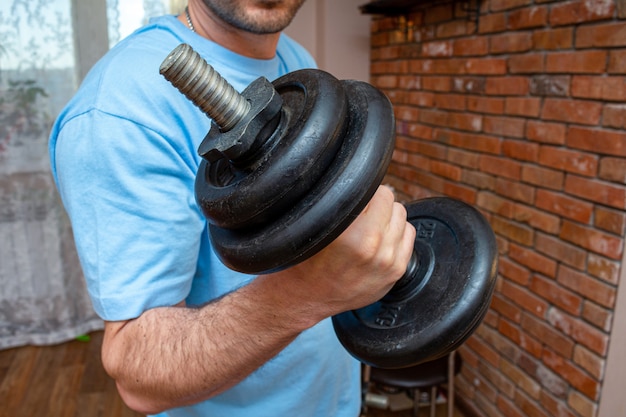 Photo dumbbell in the man hand doing fitness sport exercise at home close up