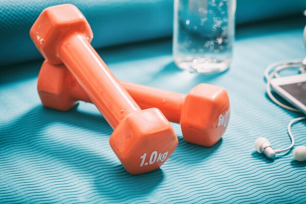 Photo dumbbells and a bottle of water on a yoga mat