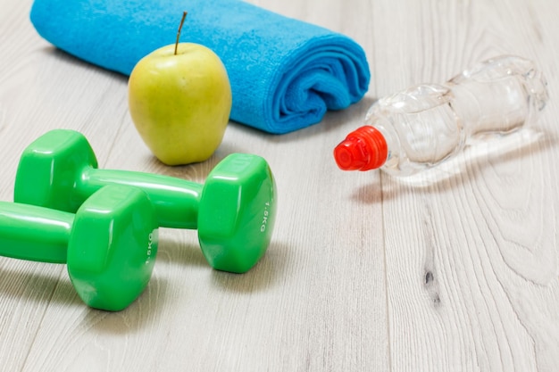 Dumbbells and different tools for fitness on floor in room