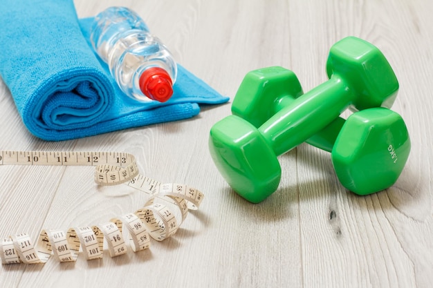 Dumbbells and different tools for fitness on floor in room