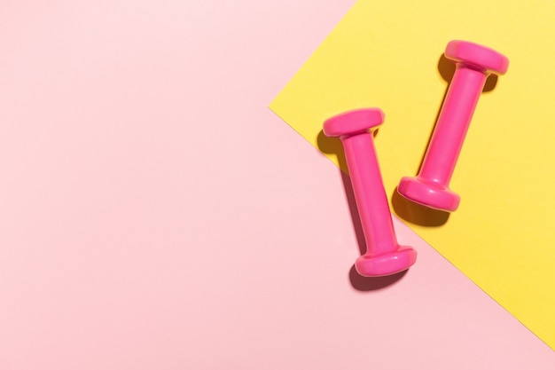 Dumbbells flat lay on pink and yellow