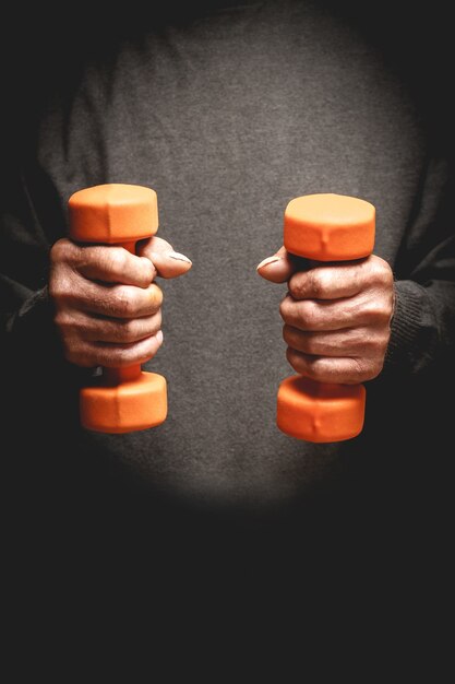 Dumbbells in the hands of an elderly man 