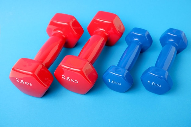 Dumbbells in a plastic sheath on a blue background Training workout equipment Sport and exercises