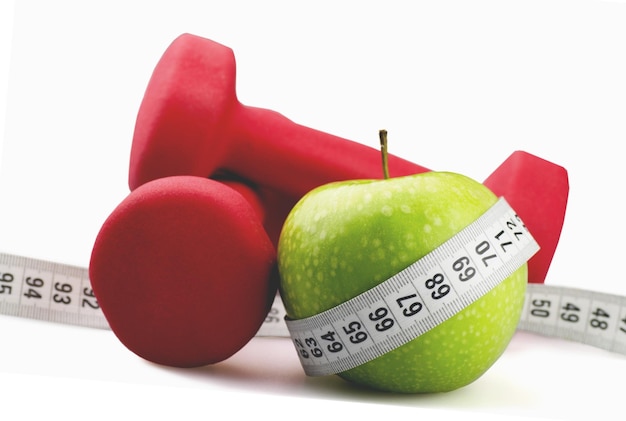 Dumbbells with measuring tape and apple for diet concept on background