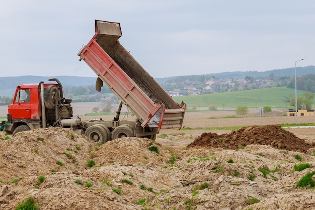 Dump truck unloading soil or sand at construction site