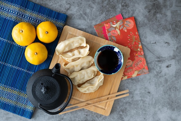 Dumpling with sauce on bamboo board and marble backdrop with Chinese New Year decoration Asian cuisine Copy space Top view