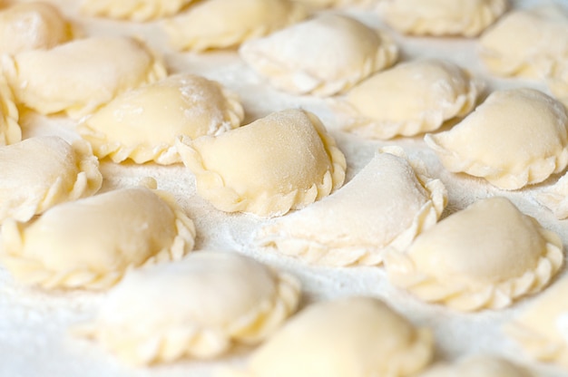 Dumplings (vareniki) with potatoes - traditional Ukrainian food. Cooking raw dumplings with potatoes