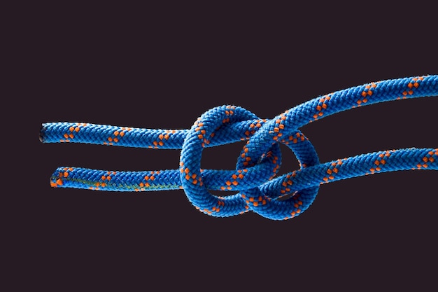 Durable colored rope for climbing equipment on a dark background knot of braided cable item for tourism and travel