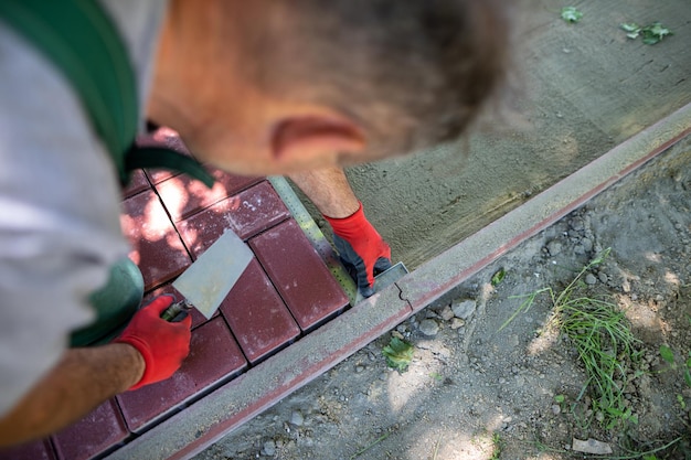 Photo during the laying of paving blocks the worker checks with a protractor the correctness of the workmanship