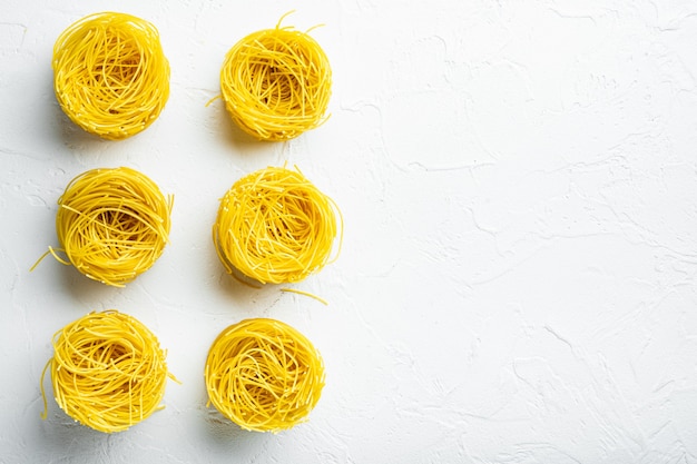 Durum wheat semolina homemade egg pasta tagliarini set, on white stone surface, top view flat lay, with copy space