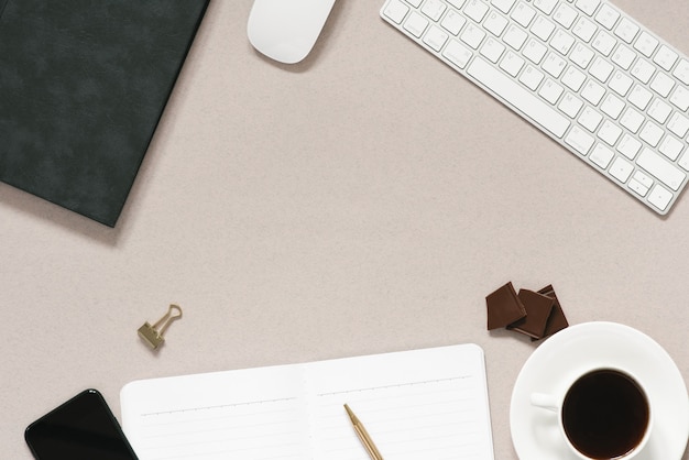 Dusty coffee office Desk with a computer, a diary with a pen, a Cup of coffee with chocolate pieces, a phone. Top view with copy space, flat lay.