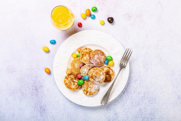 Dutch mini pancakes called poffertjes with colorful powdered sugar and candies. Healthy food concept, flat lay, top view, copy space