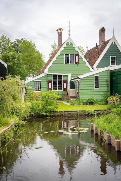 Dutch typical landscape Traditional old dutch windmill with old houses against blue cloudy sky in the Zaanse Schans village Netherlands Famous tourism place Sheep grazing on green grass