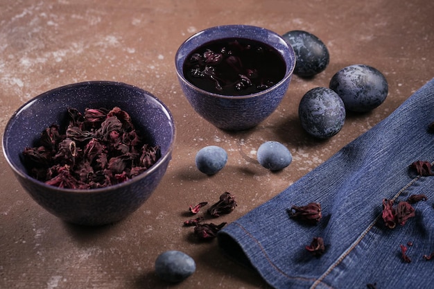 Dyed Easter eggs with marble stone effect painted with natural dye carcade tea from hibiscus flowers pussy willow branches and feathers on dark wooden background