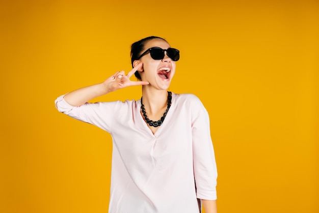 Dynamic funny modern and active girl showing victory sign with her hand screaming joyfully raising her head up