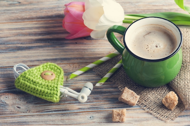 Earphones and mug of coffee with tulips