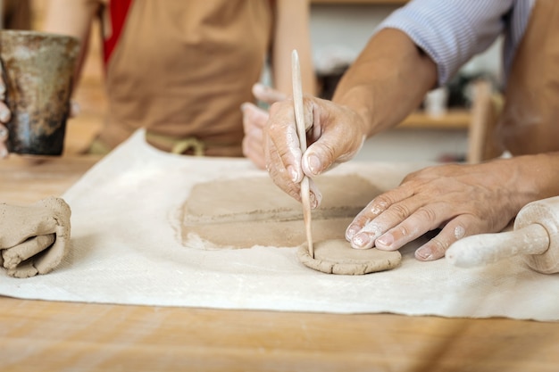 Earthenware circles. Professional potter forming little earthenware circles with his hands while working in workroom