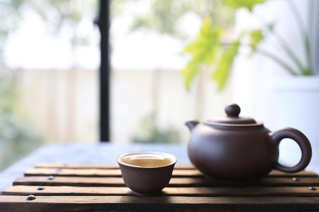 Earthenware tea cup and tea pot on wooden tray