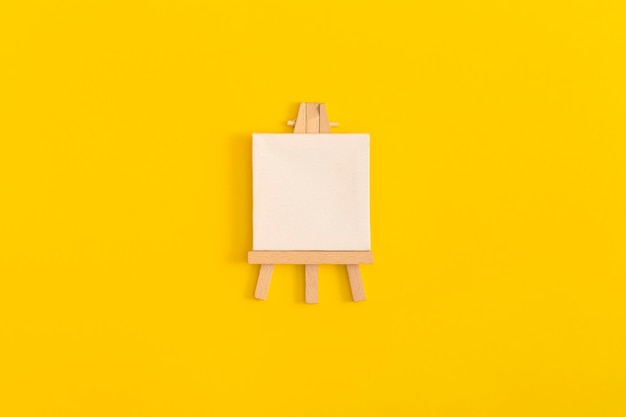 Easel on yellow background Top view with copy space