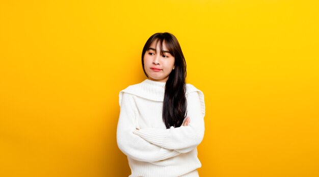 Easily upset Portrait of an Asian girl Casual upset with folded arms looking out lonely. on a yellow background