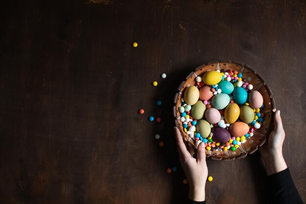 Easter background Bowl with colored Easter eggs in women's hands Space for text