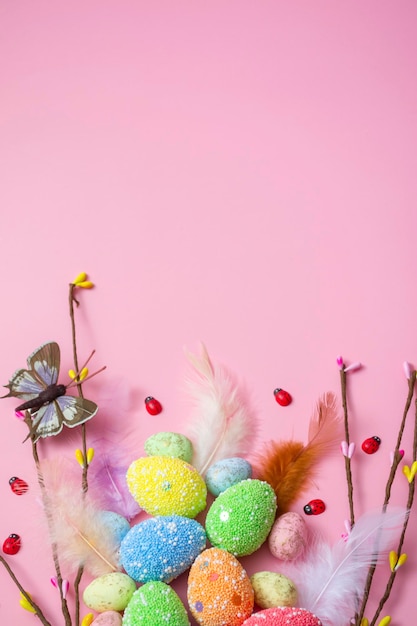 Easter background with Easter eggs and spring flowers on a pink background. flat lay, top view. Vertical format