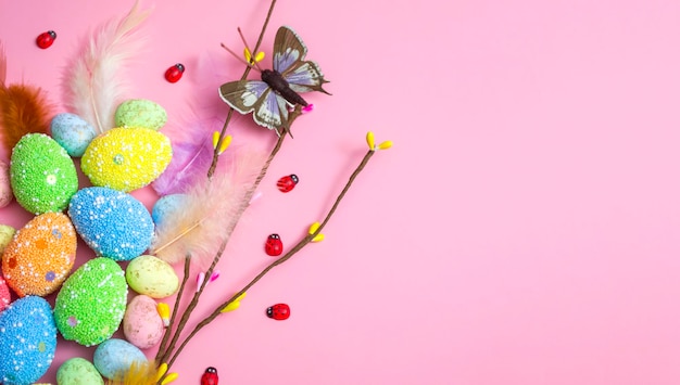 Easter background with Easter eggs and spring flowers on a pink background flat lay top view