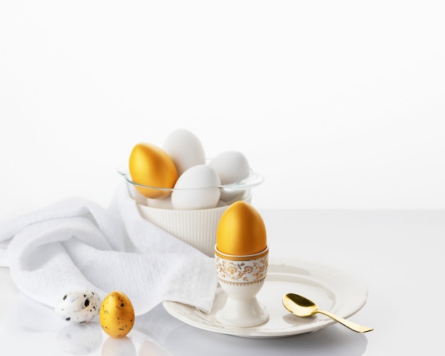 Easter breakfast concept. Soft boiled egg on a white plate with gold and white Easter eggs